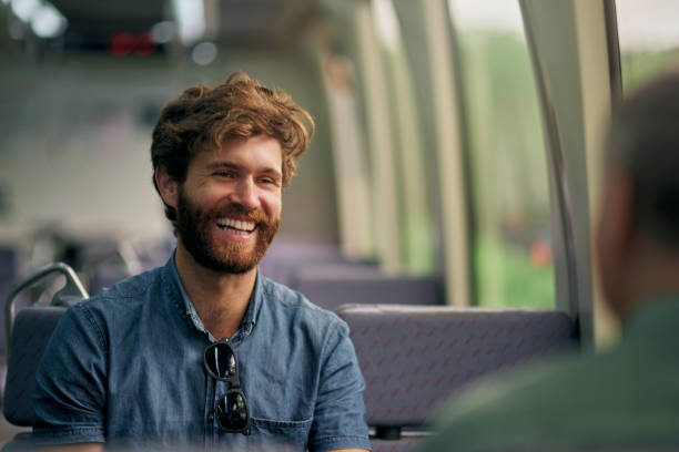 Happy, conversation and man on train for travel on vacation, weekend trip or getaway transportation. Communication, bonding and male person talking on public railway track for journey on holiday.