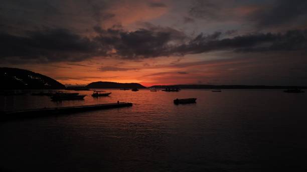 istock Serene sunset over calm sea with silhouetted boats. 2200345475
