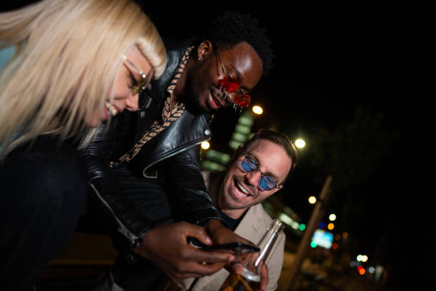 istock Friends celebrating on a night out, using mobile phone. 2200345877