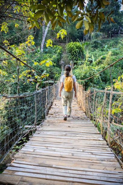 istock Woman with backpack on suspension bridge in rainforest 2200348118