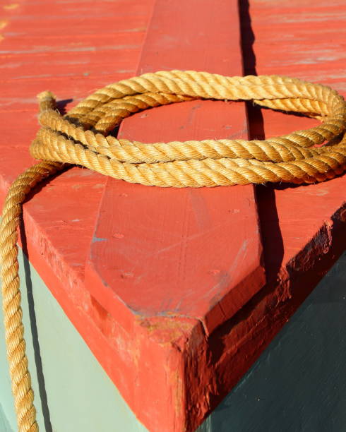 istock Coiled yellow rope resting on the red wooden surface of a boat under bright sunlight, creating strong color contrast and nautical textures 2200350148