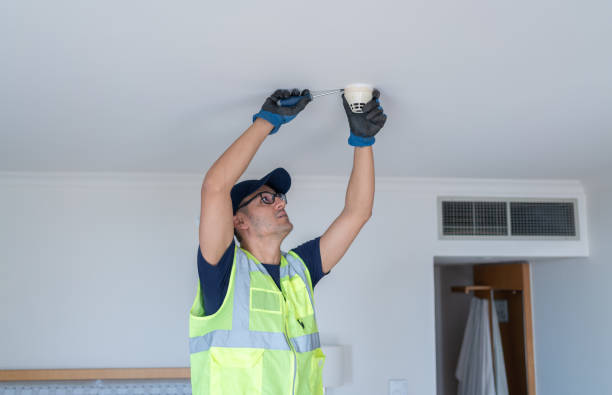 Worker Installing Smoke Detector At Hotel Room Ceiling