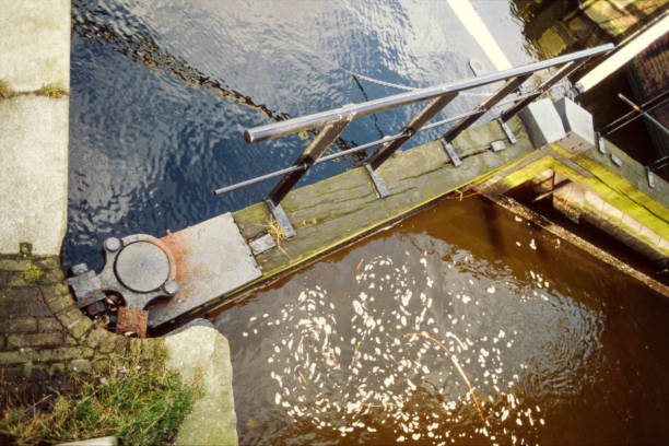 Draining the monumental Bosbaan lock and double Bosbaan drawbridge, Amsterdamse Bos, 02/22/1993, Amsterdam, The Netherlands. On the north side of the lock is the monumental classic folding bridge that connects Het Nieuwe Meer with Bosbaan with the Amsterdamse Bos from 1937, designed by architect Piet Kramer. Moving a boat in the lock by draining, discharging water.