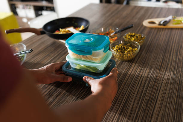 istock Person organizing food storage containers in a kitchen for meal preparation 2200355757