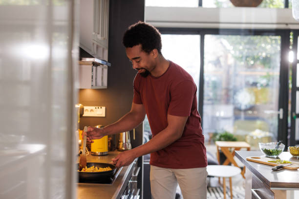 istock Man preparing food in a modern kitchen during daytime at home 2200356452