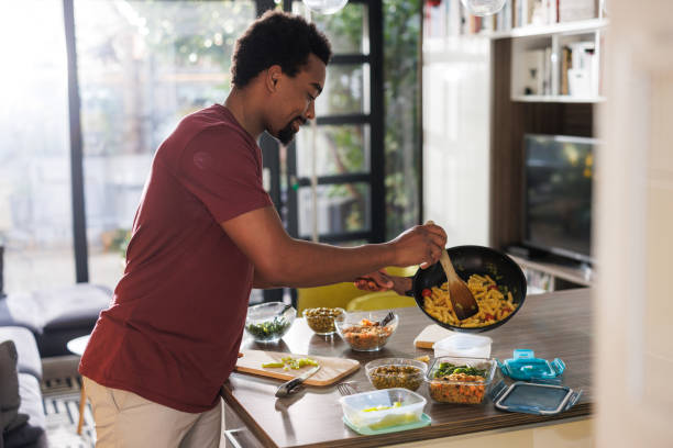 istock Man preparing food in a modern kitchen during daytime at home 2200356453