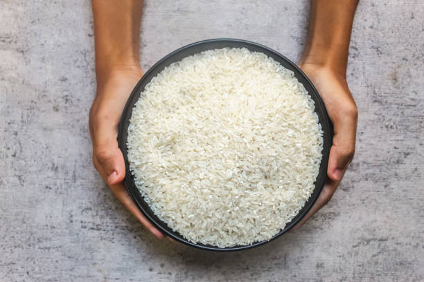 istock hand holding a bowl of raw rice 2200357886