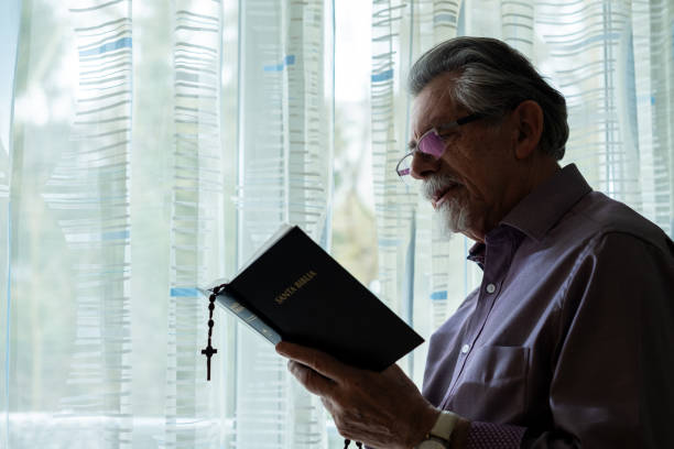 istock Elderly Man with Holy Bible in Prayer 2200363845