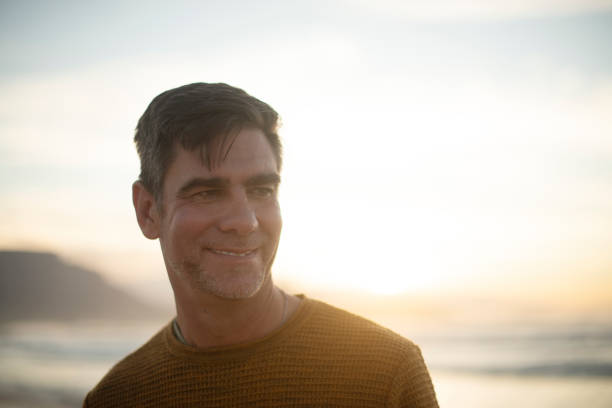 istock Man, holiday and trip for reflection on beach, sunset and remember nostalgia for inspiration. Sea, nature and waves for perspective on immigration decision, smile and tropical island for new life 2200365281