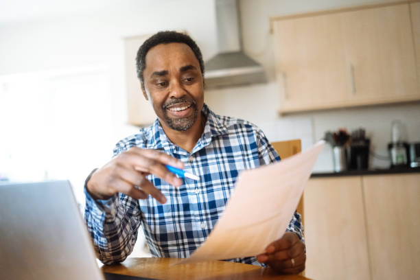 istock Serious mature entrepreneur working from home on laptop and looking at bank statement 2200366347