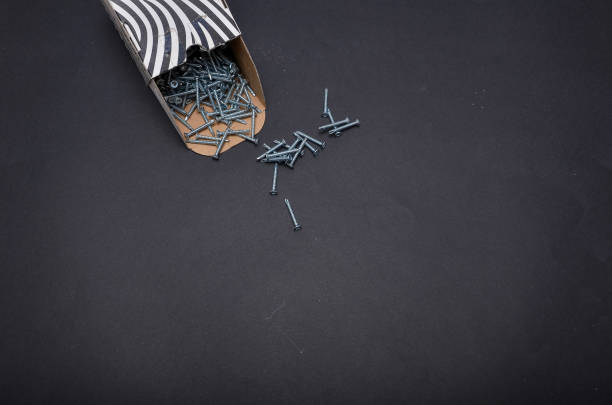 Self-tapping screws spilling from a cardboard box on a dark background, creating a scattered arrangement