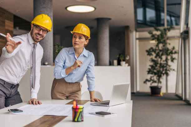 istock Architects reviewing blueprints in modern office using laptop and pointing at distance 2200368456