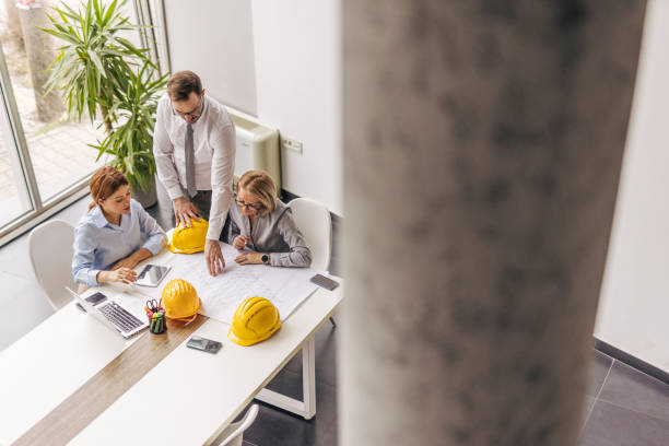 istock Architects studying blueprint in modern office during meeting 2200371119