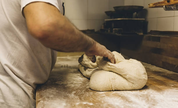 istock Baker kneading dough on wooden table in bakery 2200372842