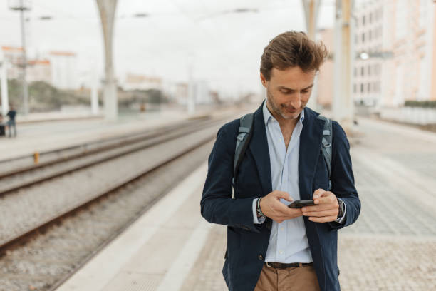 istock Businessman focused on smartphone at train station 2200376095