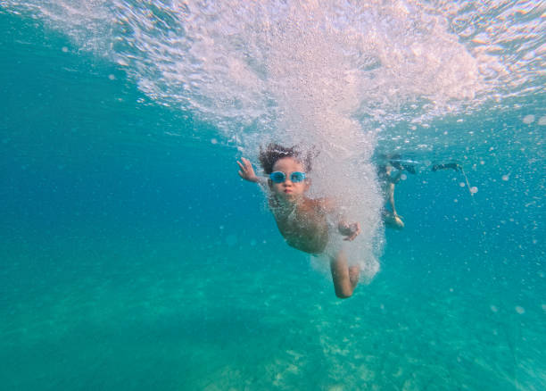 Photo of a young boy diving in the sea, wearing goggles