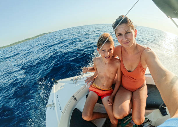 Video of a young boy in a safety west and his mom, sailing on a boat that uses wind power.