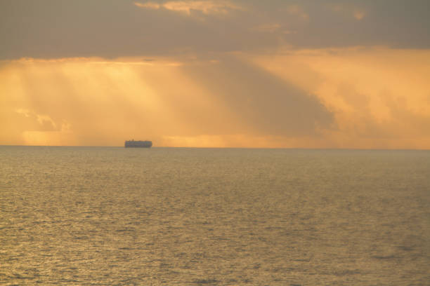 Merchant ship of car carrier type is underway at sea in the morning under dramatic sky