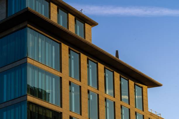 istock Modern office building with large glass windows reflecting the evening sky 2200384706