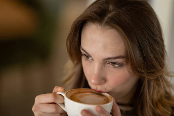 istock Young woman drinking a cappuccino with latte art in a cafe 2200386071