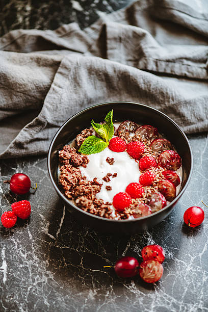 Delicious breakfast bowl with raspberries, gooseberries and chocolate chips topped with hemp seeds