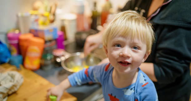 istock Smiling Toddler Boy in Blue Sweater Helping in Kitchen 2200387512