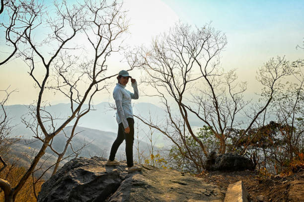 istock Woman standing on cliff with sunset 2200387795