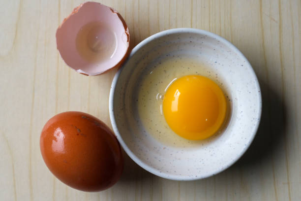 istock Cracked and whole chicken eggs on white background 2200389376