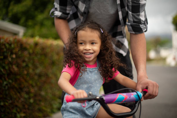 istock Teaching, child and riding bicycle on road, growth and development for girl, commuting and neighbourhood. Outdoor, learning and eco friendly transport on street, people and skills for coordination 2200389744