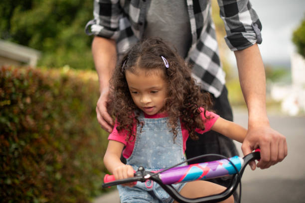 istock Learning, child and riding bicycle on road, growth and development for girl, commuting and neighbourhood. Outdoor, balance and eco friendly transport on street, people and skills for coordination 2200389771