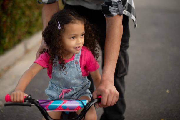 istock Road, learning and helping child with bicycle, growth and development with cycling and neighbourhood. Outdoor, hands and travel with bike on street, kid and eco friendly transport for youth or people 2200389795