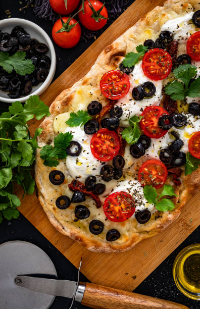 istock Roman pizza with cheese and vegetables on wooden table 2200390804