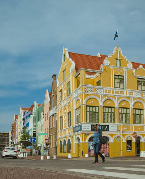 View at the historic commercial buildings in Punda: Colorful colonial architecture reflects in the water while the lively waterfront captures the charm of Willemstad.