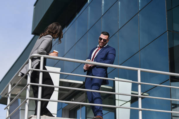 istock Two Professionals Laughing Loudly While Having Coffee Break in Front of Office Building 2200395902