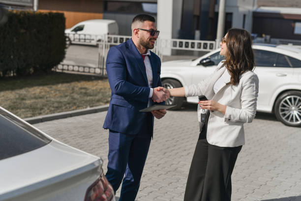 istock Cheerful Salesman Congratulating Female Customer After Successfully Finalizing Her Car Purchase 2200395932