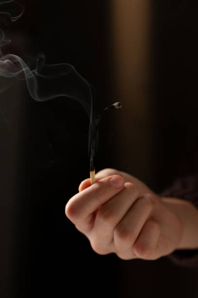 istock A woman's hand holds a long match that is extinguished and smoking on a dark 2200396061