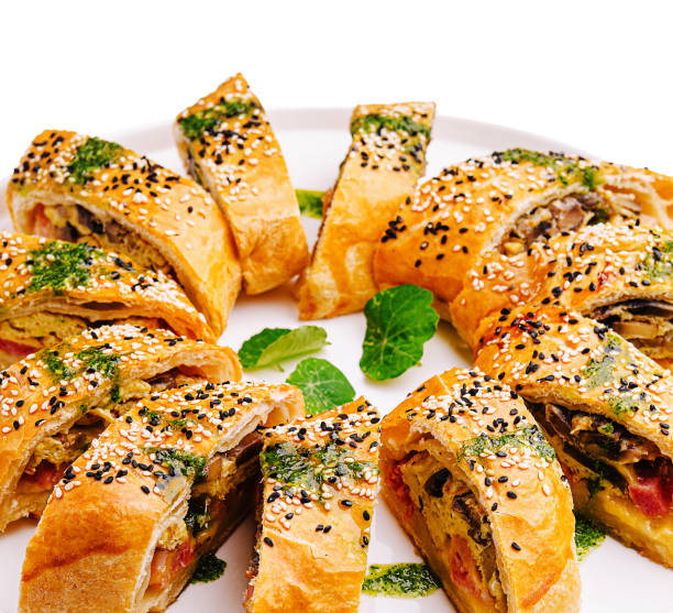 Freshly baked savory rolls arranged beautifully on a white platter with sesame seeds and herbs