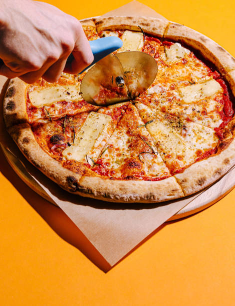 istock Delicious pizza being cut with a circular cutter on a vibrant yellow background 2200398264