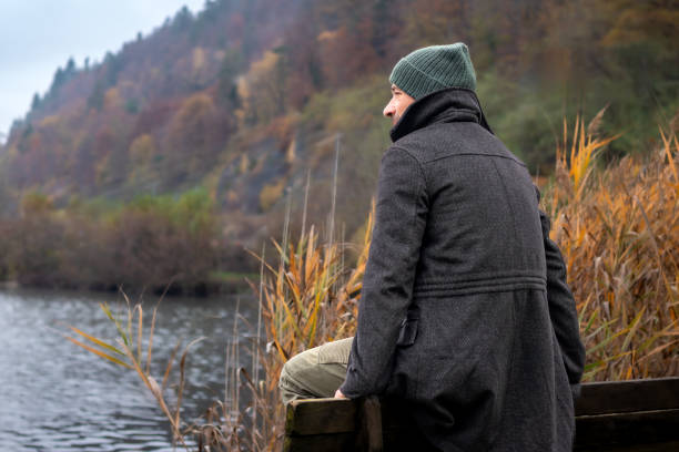 istock Man sitting on the lake shore 2200399530