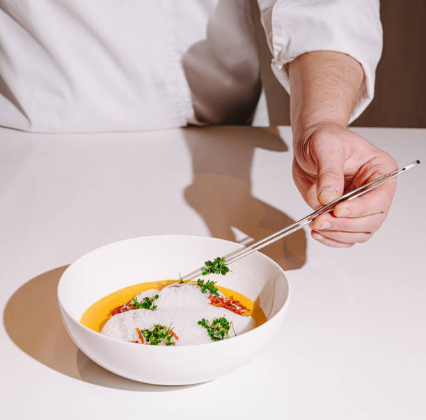 Culinary artist plating a gourmet dish with precision in a modern kitchen at twilight