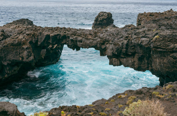 Volcanic rock formation creating a natural bridge over the ocean on El Hierro, Canary Islands
