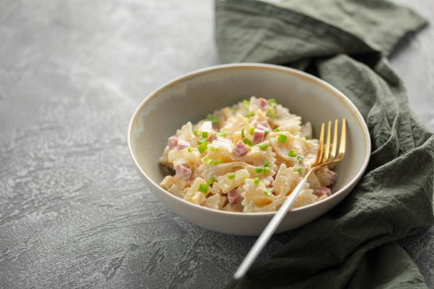 Salad with pasta, ham, pineapple, onion, cheddar cheese with sauce in a bowl on the table. Hawaiian cuisine
