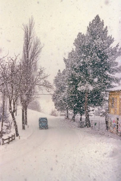 istock car along a road during a snowstorm 2200400475