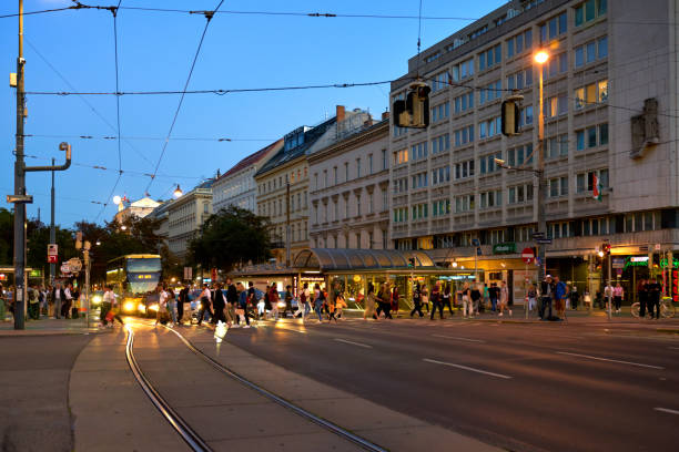 Busy Vienna intersection at dusk at the Operring by the State Opera building with vehicles and pedestrians. September 27, 2023.