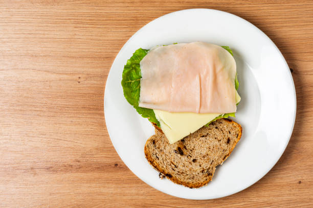 High angle view of delicious sandwhich made at home with whole grain bread with oat flajes and raisins also other ingredients in the table