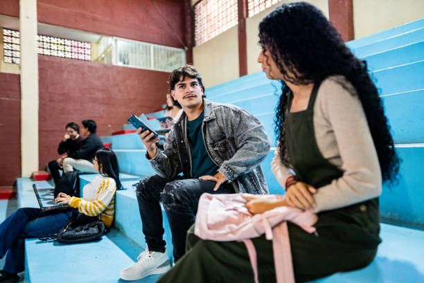istock Young man using mobile phone and talking to friend at university gymnasium 2200413088