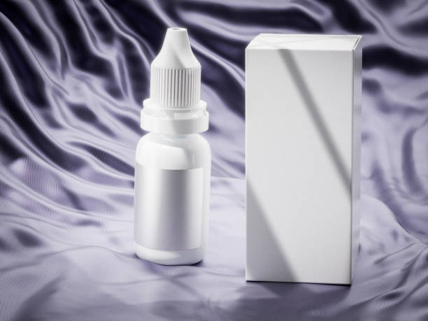 A white plastic dropper bottle with a ribbed cap and metallic label stands beside a matching white box on soft lilac satin fabric, evoking a sense of elegance and premium skincare packaging.