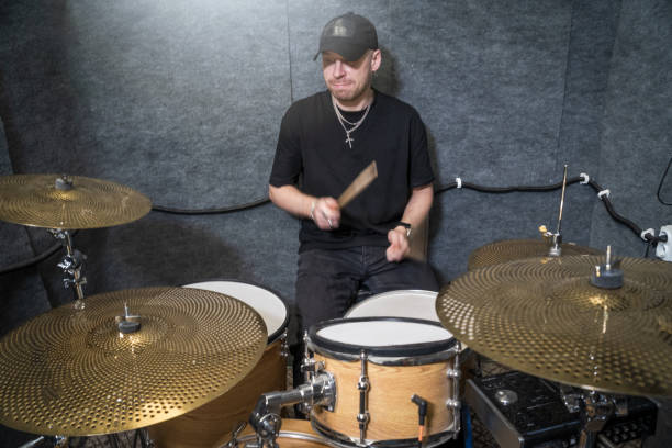 istock drummer performing in professional soundproof rehearsal studio, playing drum kit. Musician practicing rhythm and live performance for rock band session 2200419077