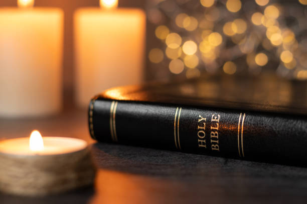 istock Holy bible book and candles burning with shiny bokeh background 2200425107