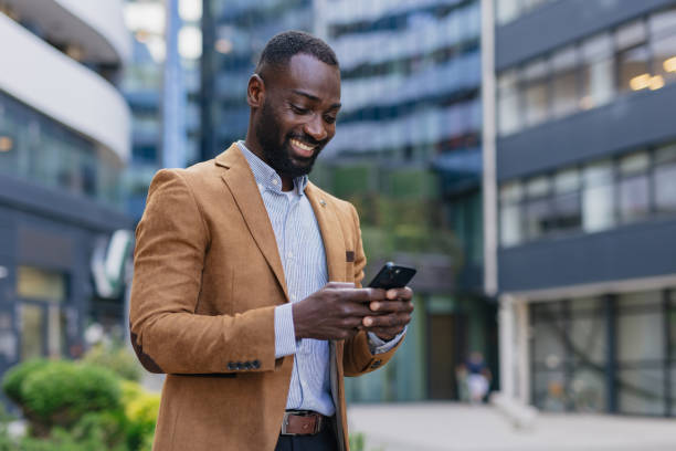 Smiling businessman using smartphone in modern city